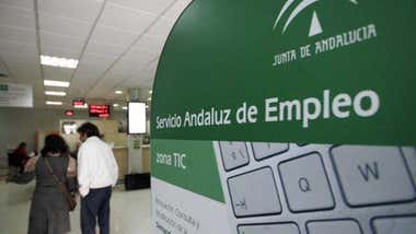 Oficina de desempleo de la Junta de Andalucía, entrada con un panel informativo y dos personas al fondo.