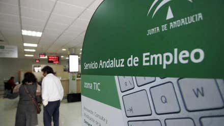 Oficina de desempleo de la Junta de Andalucía, entrada con un panel informativo y dos personas al fondo.