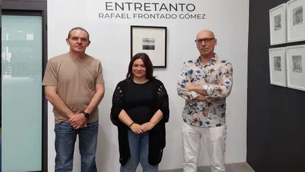 Susana Rivas con el autor posando junto a una de las obras, en pared blanca, de "Entretanto".
