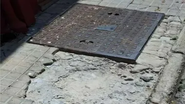 Acera en mal estado junto a una tapa de registro.
