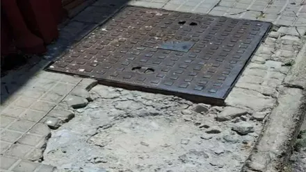 Acera en mal estado junto a una tapa de registro.
