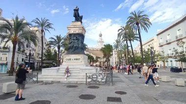 Una turista se fotografía en la estatua de Moret de la plaza de San Juan de Dios de Cádiz