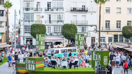 Conferencia en la Feria del Libro sobre escenario en verde, en la plaza central, de San Fernando.