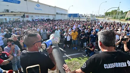 Grupo de trabajadores del metal atiende las indicaciones de lo que explica un representante con altavoz en mano.