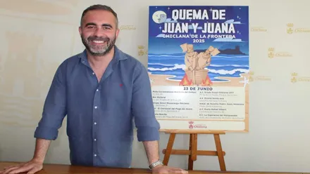 Fede Diaz, con camisa azul, junto al cartel de la quema de juanillos en Chiclana.