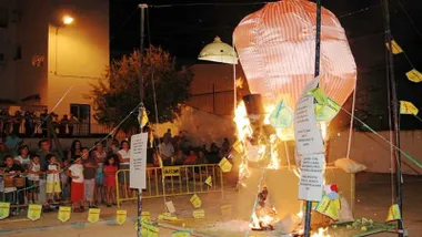 Hoguera con la quema de unos de los muñecos "juanillos", a cierta distancia los niños y niñas mirando.
