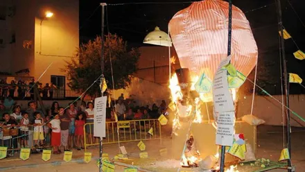 Hoguera con la quema de unos de los muñecos "juanillos", a cierta distancia los niños y niñas mirando.