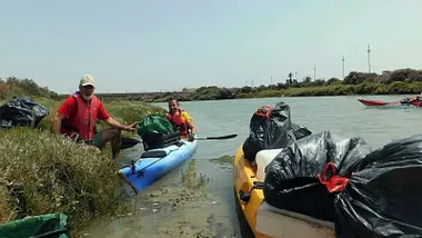 Dos personas en kayak en el Caño con bolsas de basura llenas de residuos.
