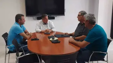 Cuatro personas reunidas en torno a una mesa de madera hablando de La Magdalena en San Fernando.