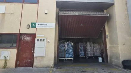 Fachada y puerta de acceso a la zona de lavandería del Puerta del Mar, la puerta está entreabierta para dejar que entre el aire.