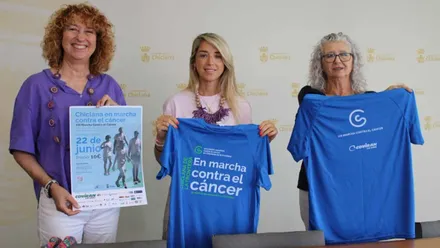 Isabel Butrón, delegada de Chiclana, junto a las organizadoras sosteniendo una camiseta del evento contra el cáncer.