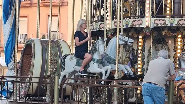 Una mujer disfruta de su 'viaje' en el tiovivo de la Plaza de la Catedral de Cádiz.