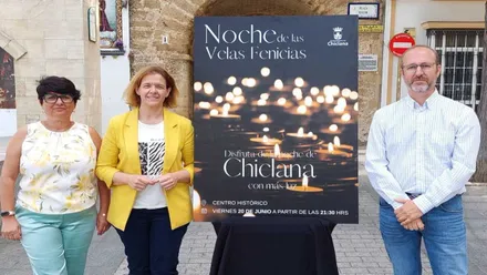 Representante municipal y organizadores junto al cartel, negro con velas amarillas, de "La noche de las velas fenicias" de Chiclana.