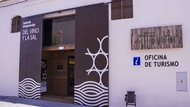 Oficina de Turismo de Chiclana con la fachada en blanco y las puertas en color marrón.