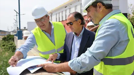 José María Román, junto a dos personas, con chalecos reflectantes, mirando el plano de la obra.