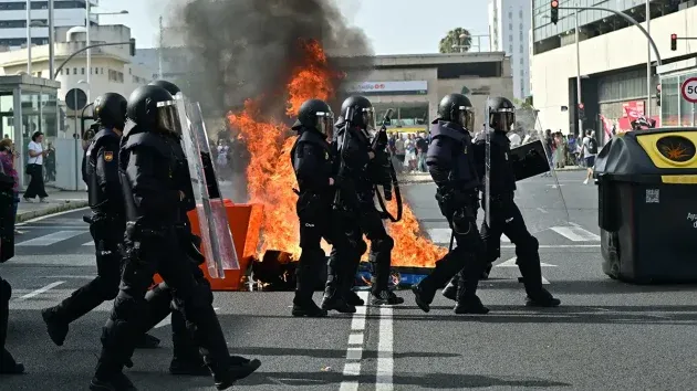 Agentes de la Policía toman posiciones ante una barricada con los manifestantes al fondo en la Avenida de la Sanidad Pública.