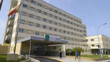 Fachada de cemento del hospital Punta Europa, a la izquierda la bandera de España.