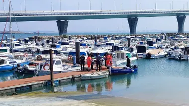 Momento en el que la mujer rescatada del agua es llevada en una camilla en el Club Náutico Viento de Levante de Cádiz