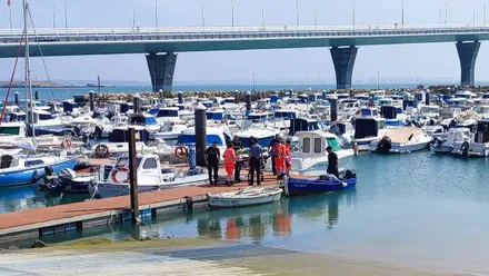 Momento en el que la mujer rescatada del agua es llevada en una camilla en el Club Náutico Viento de Levante de Cádiz