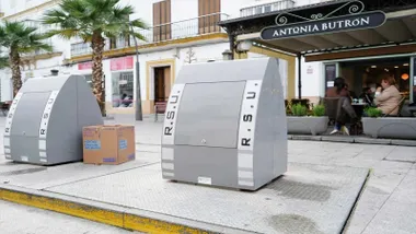 Dos contenedores grises, de residuos, en una calle de Chiclana.