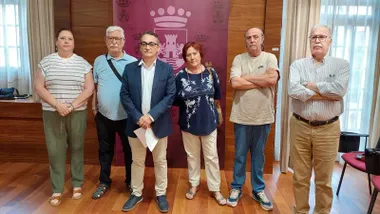 Representantes ciudadanos en pie junto al delegado Francis Salado de Chiclana, de fondo el escudo de la ciudad en tonos burdeos.