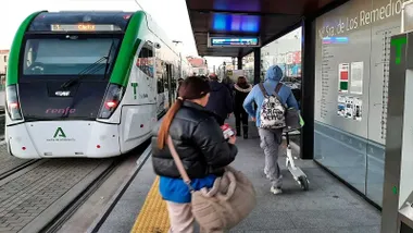 Parada de Trambahía con pasajeros en el andén. El tres es de color verde y blanco.