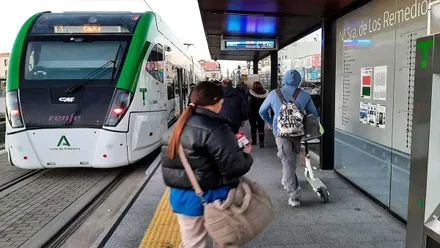 Parada de Trambahía con pasajeros en el andén. El tres es de color verde y blanco.