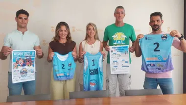 Representante municipal y del Club de Volley en pie sosteniendo camisetas en las manos.