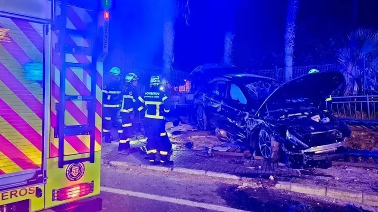 Coche seriamente dañado y los bomberos interviniendo tras un accidente en la entrada de Cádiz