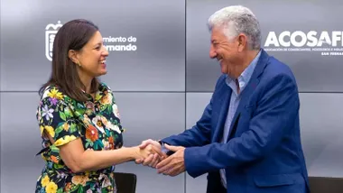Patricia Cavada con vestido estampado y Manuel Luna, con chaqueta azul, se estrechan la mano tras la firma del convenio.