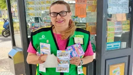 La vendedora de cupones Adela mostrando los cupones, luce chalequillo verde de la ONCE.