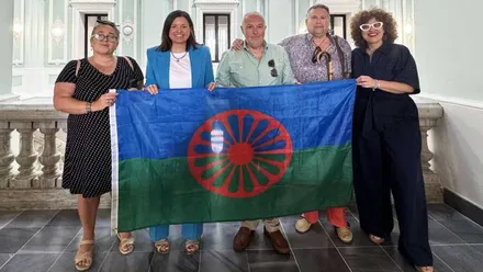 Patricia Cavada junto a miembros de la asociación portando la bandera romaní.