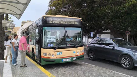 Un autobús de Cádiz con el carteld e "servicios mínimos" recoge pasajeros en la parada de La Caleta, frente al árbol del Mora.