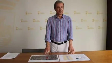 Rodolfo Pérez, delegado de Urbanismo, con camisa celeste, apoyado en una mesa de madera, presentando el proyecto.