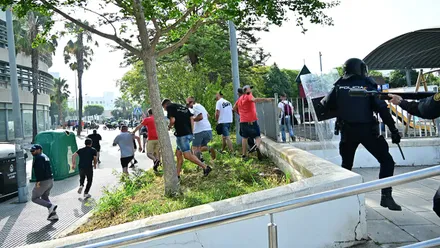 Varios trabajadores del metal corren delante de un policía antidisturbios que los persigue
