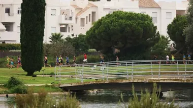 Corredores en una competición deportiva, por un parque con mucho verde y árboles, en Rota.