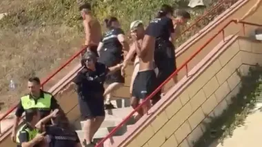 Una agente de la Policía Local se lleva a un menor en la Playa de Santa María del Mar.