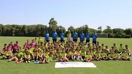 Muchos niños y niñas con camiseta amarilla fluorescente en el campo de fútbol de Novo Sancti Petri.