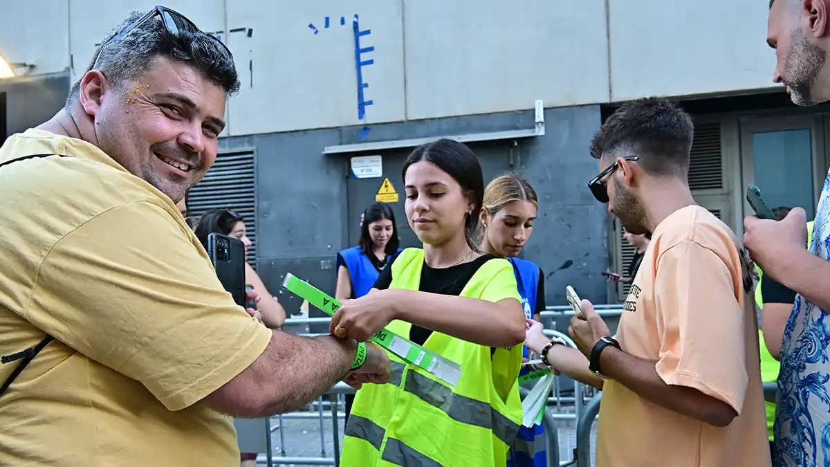Una empleada del acceso le coloca la pulsera de entrada a un asistente al concierto de Jennifer López.