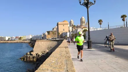 Un hombre hace deporte por el Campo del Sur de Cádiz con la Catedral al fondo