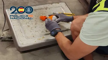 Agente de la Policía Nacional abriendo una falsa naranja de hachís.