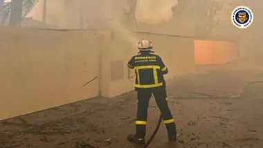 Bombero, de azul, con la manguera apagando el incendio.