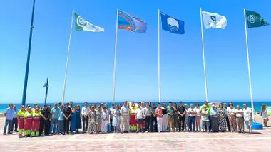 Fuerzas municipales e implicados en el momento del izado de banderas en la playa de La Barrosa.
