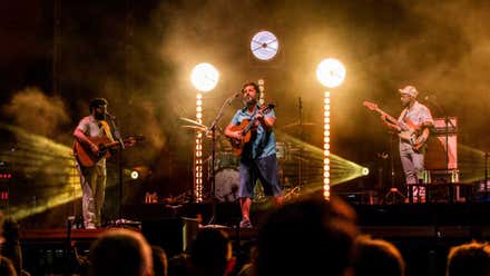 El Kanka tocando en el escenario con tonos de focos amarillos.