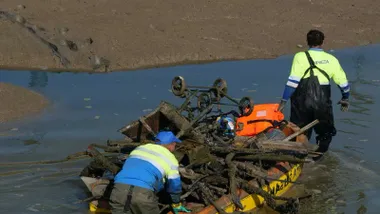 Operarios retirando objetos en una barca en el río Iro.