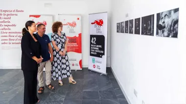 La alcaldesa de San Fernando, de negro, mirando fotografías de la exposición en blanco y negro.