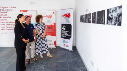 La alcaldesa de San Fernando, de negro, mirando fotografías de la exposición en blanco y negro.