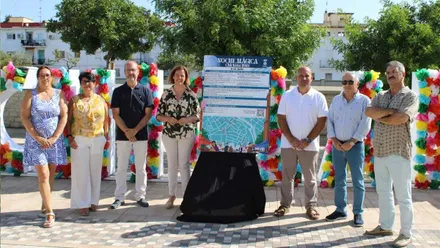 La delegada Manuela Pérez, con camisa estampada, junto al cartel de la "Noche Mágica" de Chiclana.