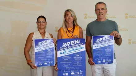 Isabel Butrón en el centro de la imagen, con camisa naranja, sosteniendo el cartel y acompañada de los organizadores.