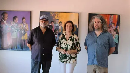 Manuela Pérez junto a Benítez posando delante de unos cuadros de la exposición "Otras músicas".